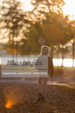 Sweden, Vastergotland, Lerum, Back view of girl (8-9) walking in riverside park