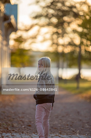 Sweden, Vastergotland, Lerum, Portrait of girl (8-9) walking in riverside park, looking over shoulder