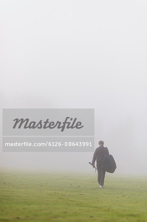 Sweden, Vastmanland, Teenage boy (14-15) walking in green field in fog