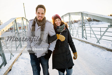 Sweden, Vasterbotten, Umea, Young couple walking on footbridge in winter