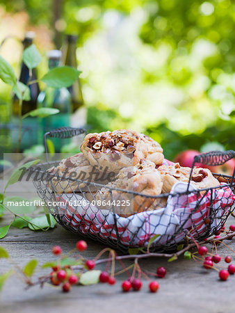 Sweden, Sweet apple and hazelnut buns in metal basket on wooden table