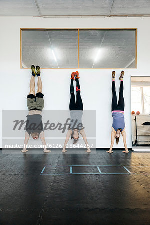 Germany, Young women and man practicing handstand in gym