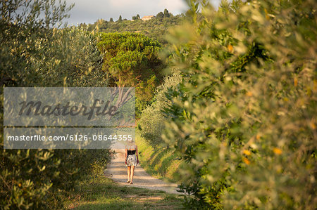 Italy, Tuscany, Dicomano, Woman walking along road in vineyard