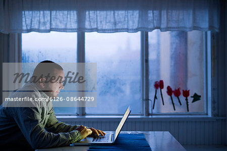 Finland, Man sitting at table and using laptop