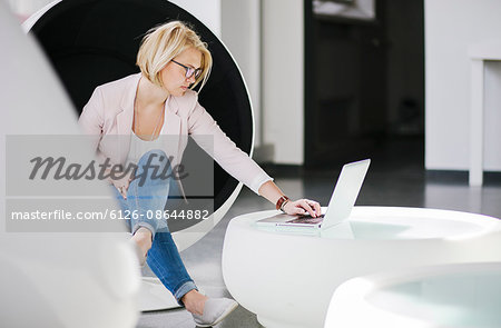 Finland, Helsinki, Woman using laptop in ball chair