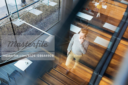 Finland, Young businessman walking upstairs and talking on phone