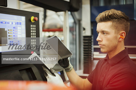 Worker with part at control panel in steel factory