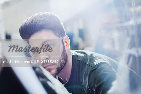 Serious worker examining piece in steel factory Serious worker examining piece in steel factory