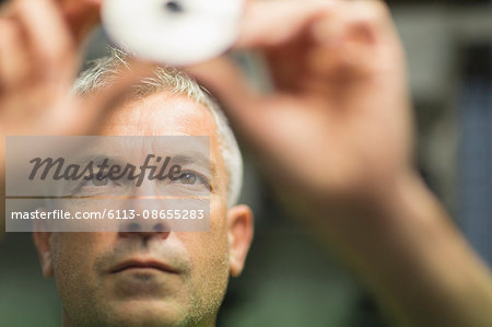 Focused worker examining part in steel factory Focused worker examining part in steel factory