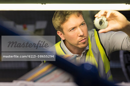 Focused worker inspecting part in steel factory Focused worker inspecting part in steel factory