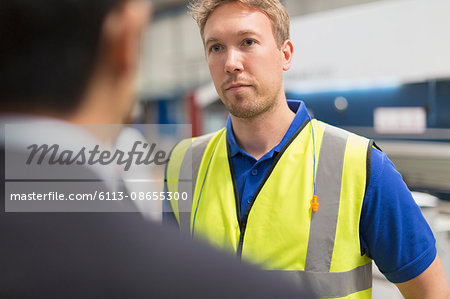 Serious worker listening to manager in steel factory