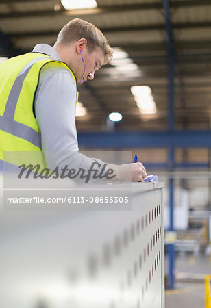 Supervisor writing on clipboard in steel factory