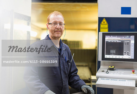 Portrait confident worker at control panel in steel factory