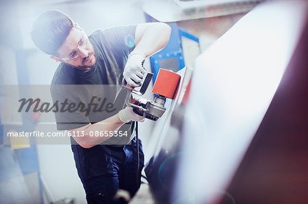 Worker sanding steel in steel factory Worker sanding steel in steel factory