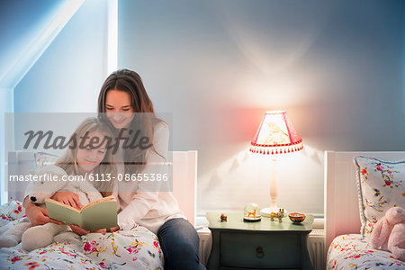 Mother and daughter reading book in bedroom