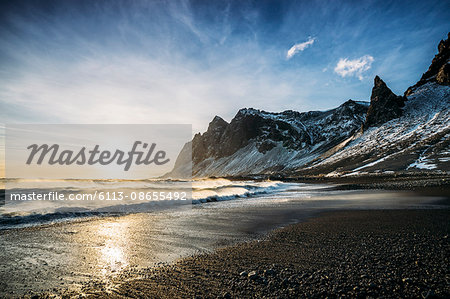 Sun setting over tranquil beach and snowy mountain, Iceland