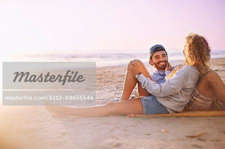 Smiling couple relaxing and talking on sunset beach