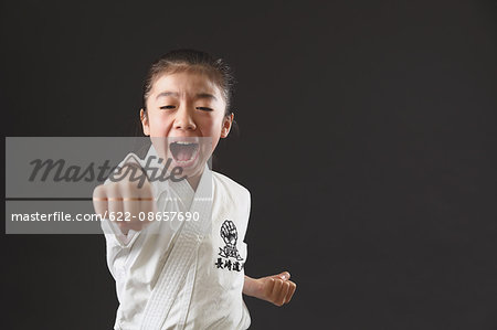 Japanese kid in karate uniform on black background