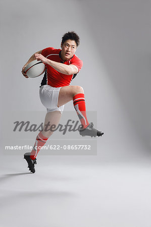 Portrait of Japanese rugby player running with ball