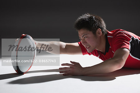 Portrait of Japanese rugby player diving to score a try