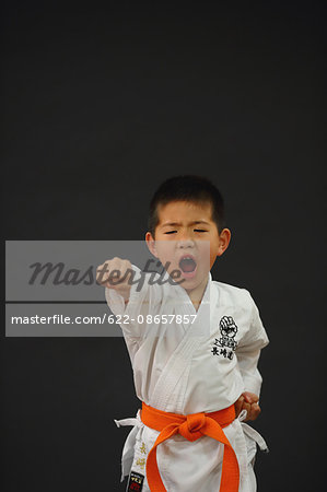 Japanese kid in karate uniform on black background
