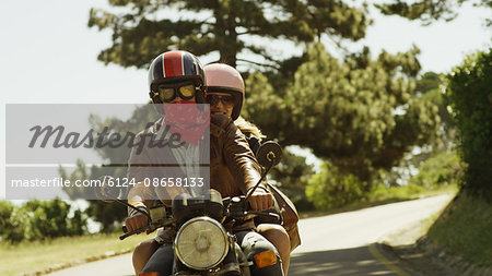 Young couple riding motorcycle on sunny road