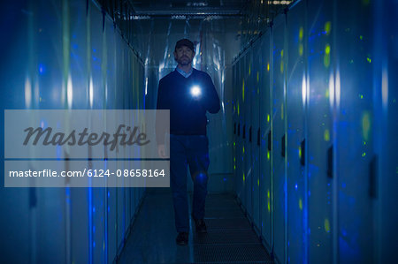Server room technician with flashlight in dark corridor