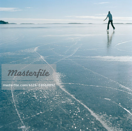 Sweden, Stockholm Archipelago, Uppland, Varmdo, Bjorno, Mid adult woman ice skating on frozen lake