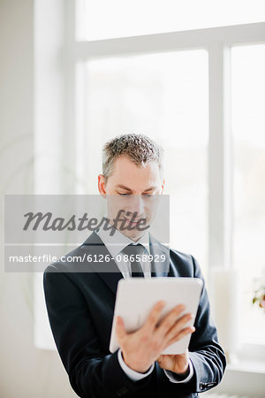 Sweden, Mid adult man holding digital tablet