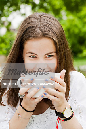 Sweden, Sodermanland, Stockholm, Portrait of young woman drinking from cup in park