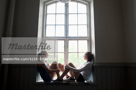 Two girls (14-15) sitting on window sill
