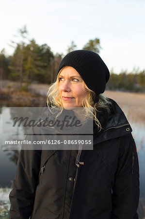 Sweden, Ostergotland, Lotorp, Mature woman looking away, forest in background