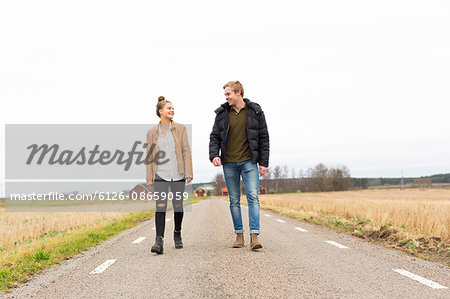 Sweden, Ostergotland, Mjolby, Teenage girl (14-15) and young man walking along country road