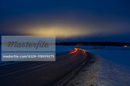 Sweden, Sodermanland, Skavsta, Light trail on road in winter at dusk
