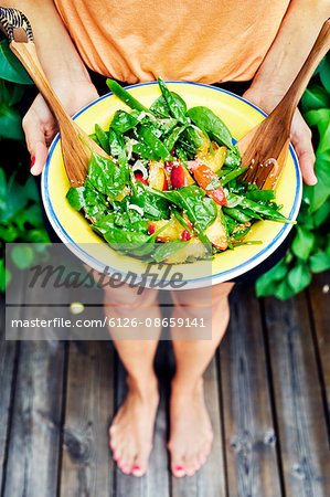 Sweden, Uppland, Danderyd, Young woman holding plate with salad