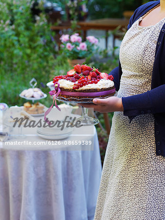 Sweden, Woman carrying cake topped with fresh berries
