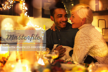 Affectionate couple with dog at candlelight Christmas table