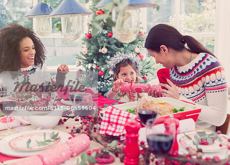 Mother and daughter pulling Christmas cracker at dinner