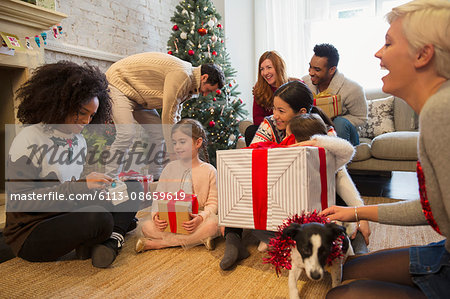 Friends and family opening Christmas gifts in living room