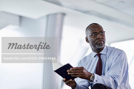 Pensive businessman with journal looking away