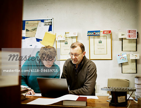 Two people seated at a computer in a small bookbinding business.
