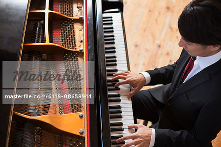 Young man playing on a grand piano in a rehearsal studio.