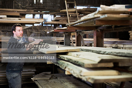 Man working in a carpentry workshop, measuring a plank of wood.