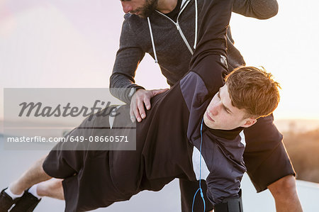 Mid adult man helping young man exercise