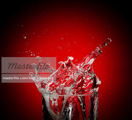 Water and droplets splashing against red background Water and droplets splashing against red background