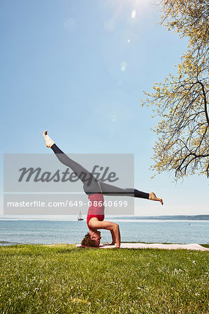 Side view of woman doing headstand, legs apart