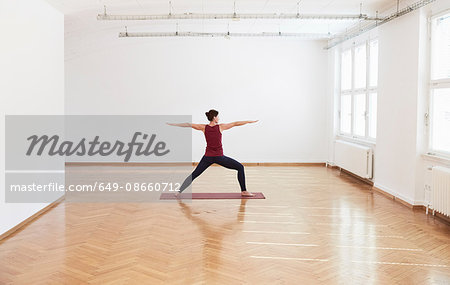 Woman in exercise studio arms open legs apart in yoga position