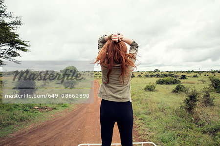 Woman enjoying ride on top of vehicle in wildlife park, Nairobi, Kenya