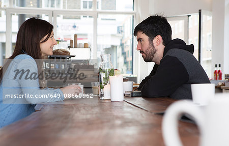 Mid adult couple sitting at cafe table with coffee, chatting