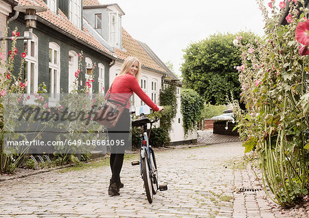 Woman pushing bicycle on cobblestone street, Aarhus, Denmark
